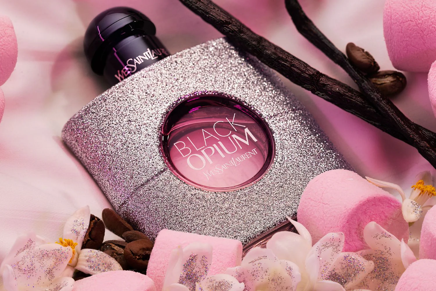 Black opium perfume, the bottle is surrounded with silver glitters. the perfume packaging color is silver & black with a transparent circle in the middle showing the color of the perfume. The color is pink. Photo credit: Sephora